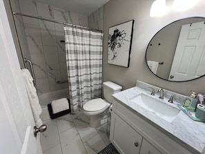 Une salle de bain Ă©quipĂ©e dâune douche, de toilettes, dâun lavabo et dâun miroir.