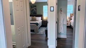 Ein Hotelzimmer mit Bett, Bademantel, Nachttisch und einem Gemälde an der Wand.