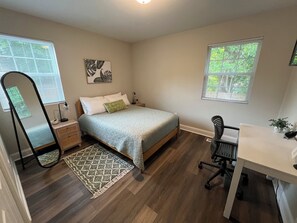A bedroom with a bed, bedside tables, a desk, a chair, a mirror, and a window. - Quiet 2BR Cottage - 3.9 miles to downtown Durham + close to Duke, DPAC and NCCU (Durham)