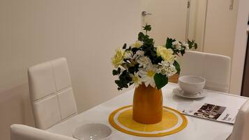 A dining table with chairs, a vase with flowers, and a bowl on the table.