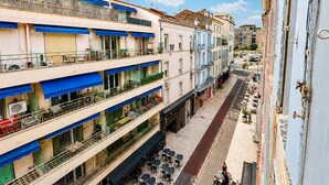 Un immeuble à plusieurs étages doté de balcons, d’un espace extérieur aménagé pour s’asseoir et donnant sur la rue.