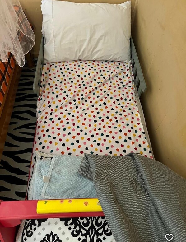 Una cama pequeña con piso estampado de cebra, almohada blanca y colcha de lunares.
