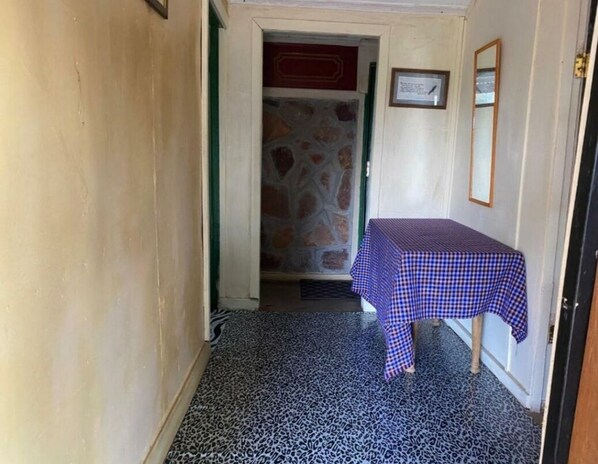 A narrow hallway with a checkered table and a stone wall.