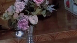 Un soggiorno con un tavolino rotondo, un vaso con fiori, una poltrona marrone e un mobiletto bianco decorato.