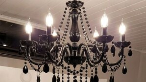 Una camera da letto con un grande specchio, una cassettiera bianca e un lampadario.