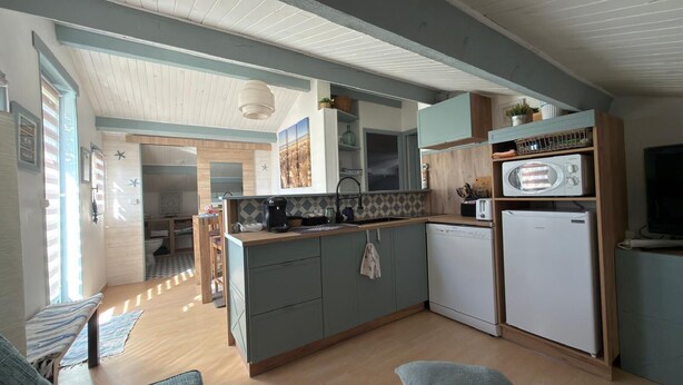 Cozinha compacta com ilha central, micro-ondas e máquina de lavar louça.