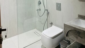 Un baño moderno con ducha de vidrio, inodoro blanco y lavamanos de mármol.
