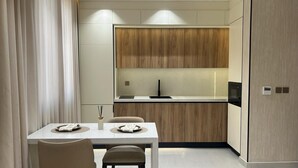 Una cocina moderna con salpicadero de madera, encimera blanca y un comedor con mesa y sillas.