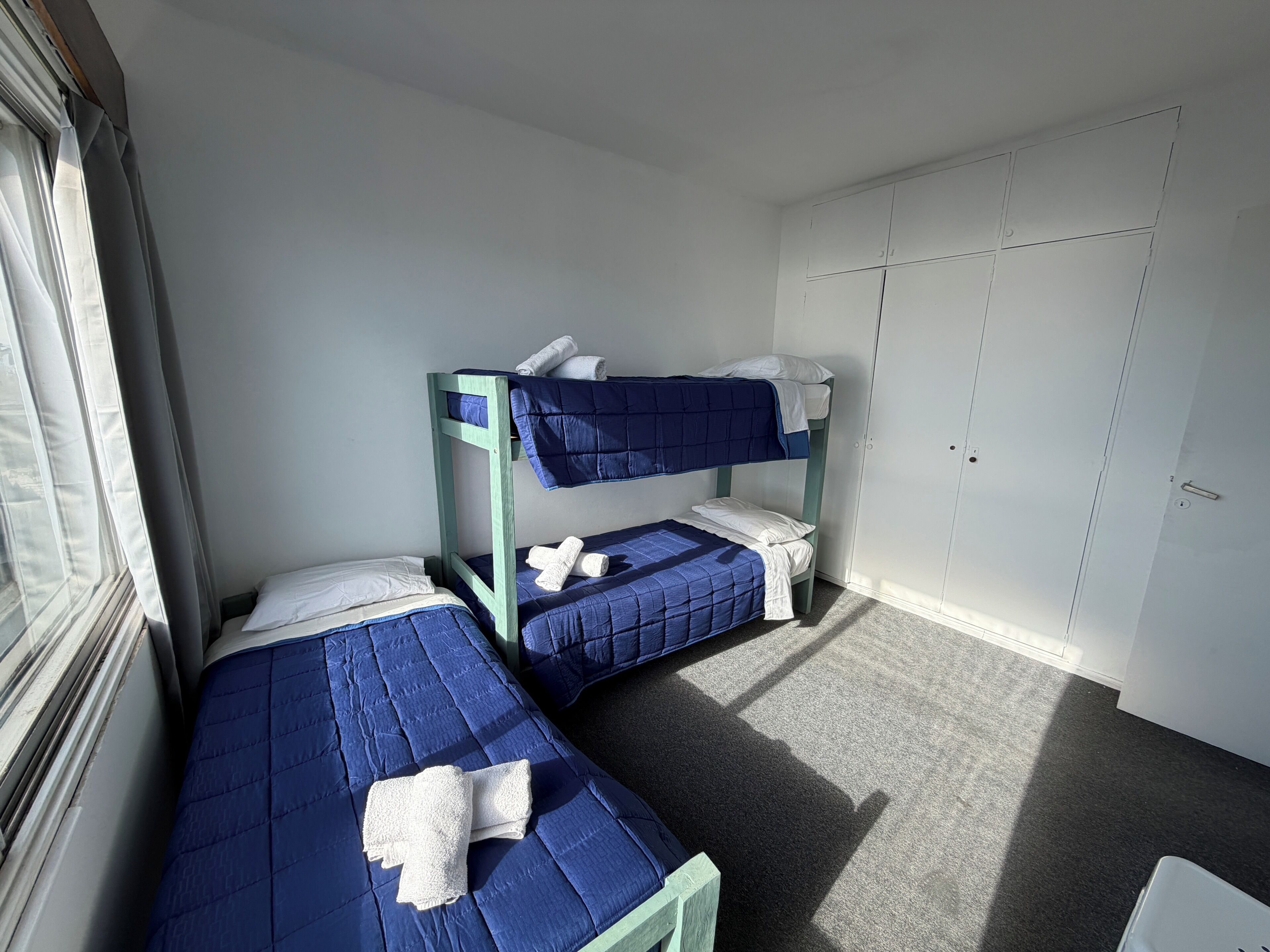 Ein Zimmer mit zwei Etagenbetten, einem Kleiderschrank und einem Fenster.