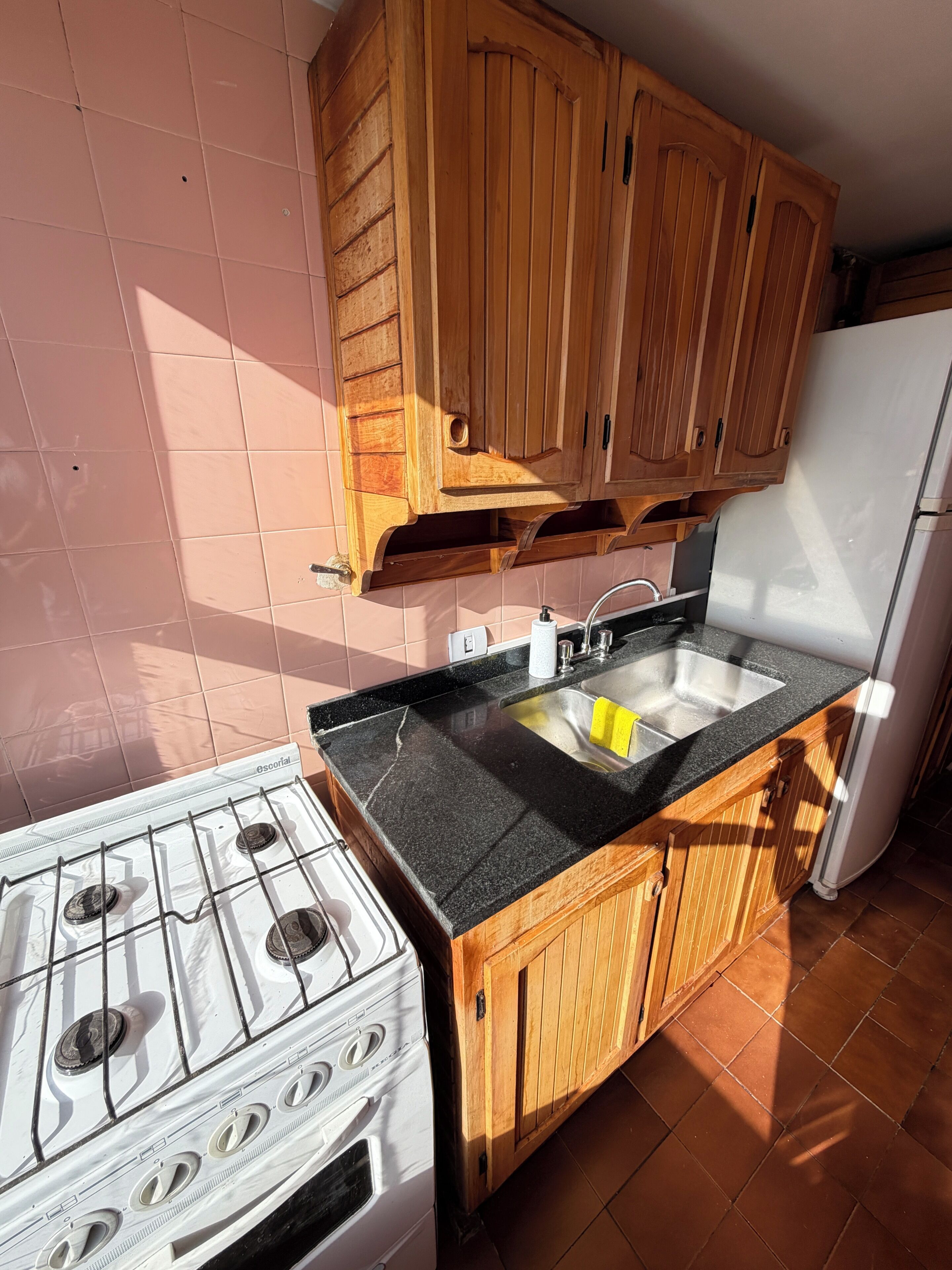 A kitchen with wooden cabinets, a gas stove, a sink, and a refrigerator.