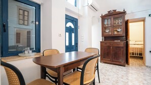 Un comedor con mesa de madera y sillas de mimbre, una puerta azul y un mueble con puertas de vidrio.