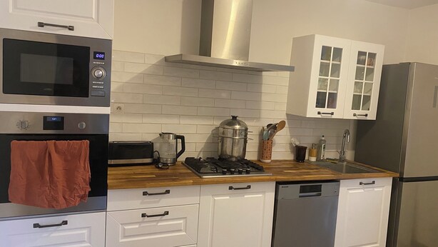 Uma cozinha moderna com armários brancos, fogão de aço inoxidável, micro-ondas e lava-louças.