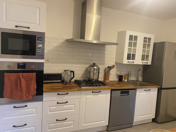 A modern kitchen with white cabinetry, a stainless steel range, a microwave, and a dishwasher. - Charming house in Toulon (Toulon)