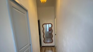 Um corredor com piso estampado, uma porta à esquerda e um lustre.