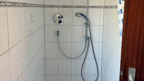 Un espace douche équipé d’un pommeau de douche à main, d’un robinet mural et d’un rideau de douche.