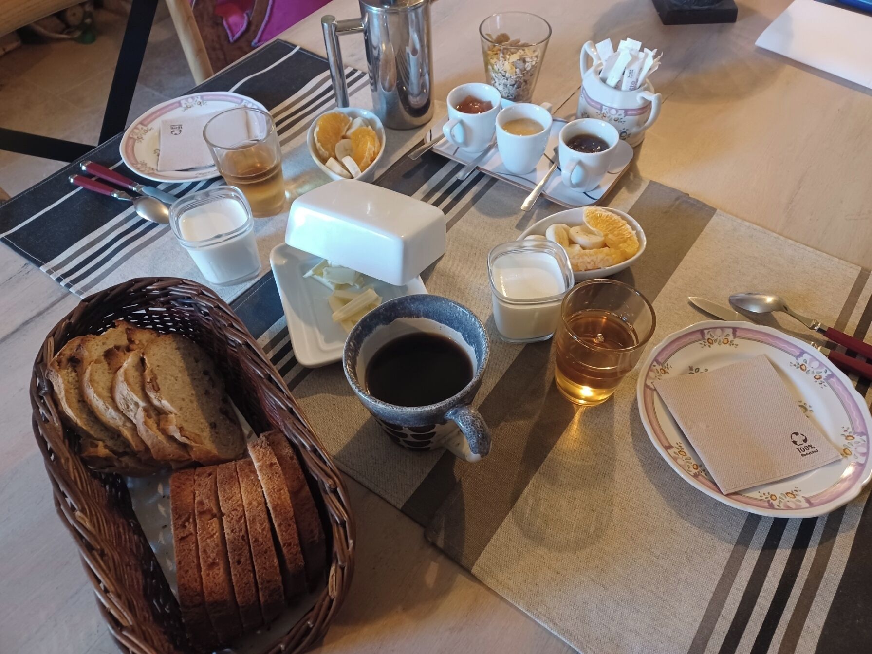 A breakfast setting with bread, coffee, and fruit.