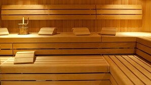 A sauna with wooden benches and a central heater. - guestified. GRAND AIRPORT Hotel (Ratingen)