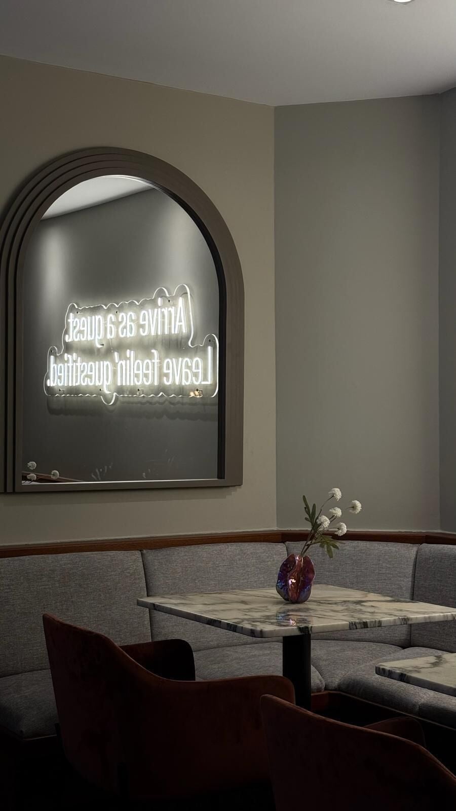 A modern interior with a curved wall mirror, a marble table, and a vase with flowers.