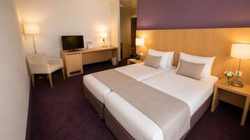Een hotelkamer met een groot bed, een bureau, een televisie en een stoel.