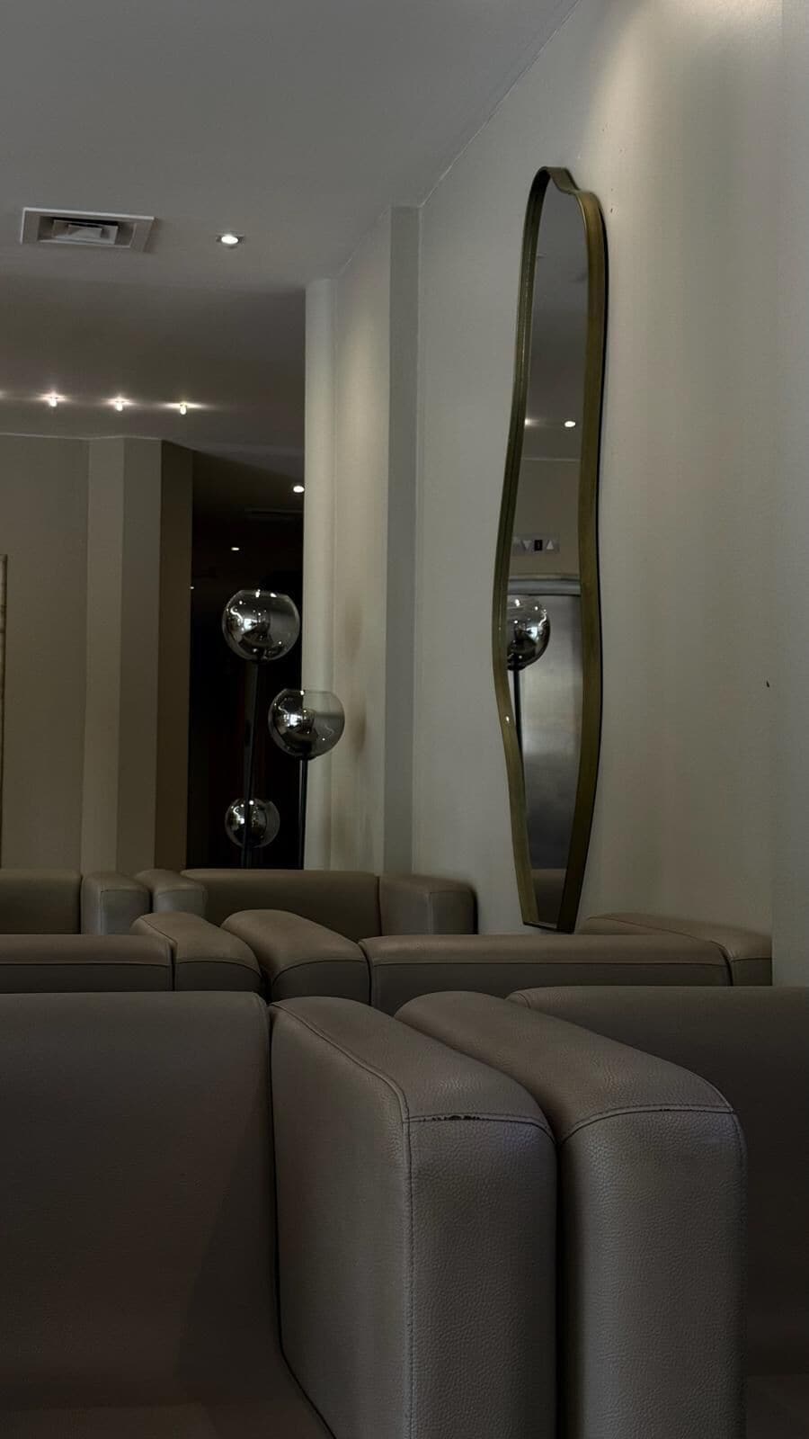 Een modern interieur met een bank en een grote spiegel.