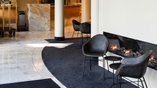 Moderni aula, jossa on vastaanottotiski, oleskelualue ja takka.