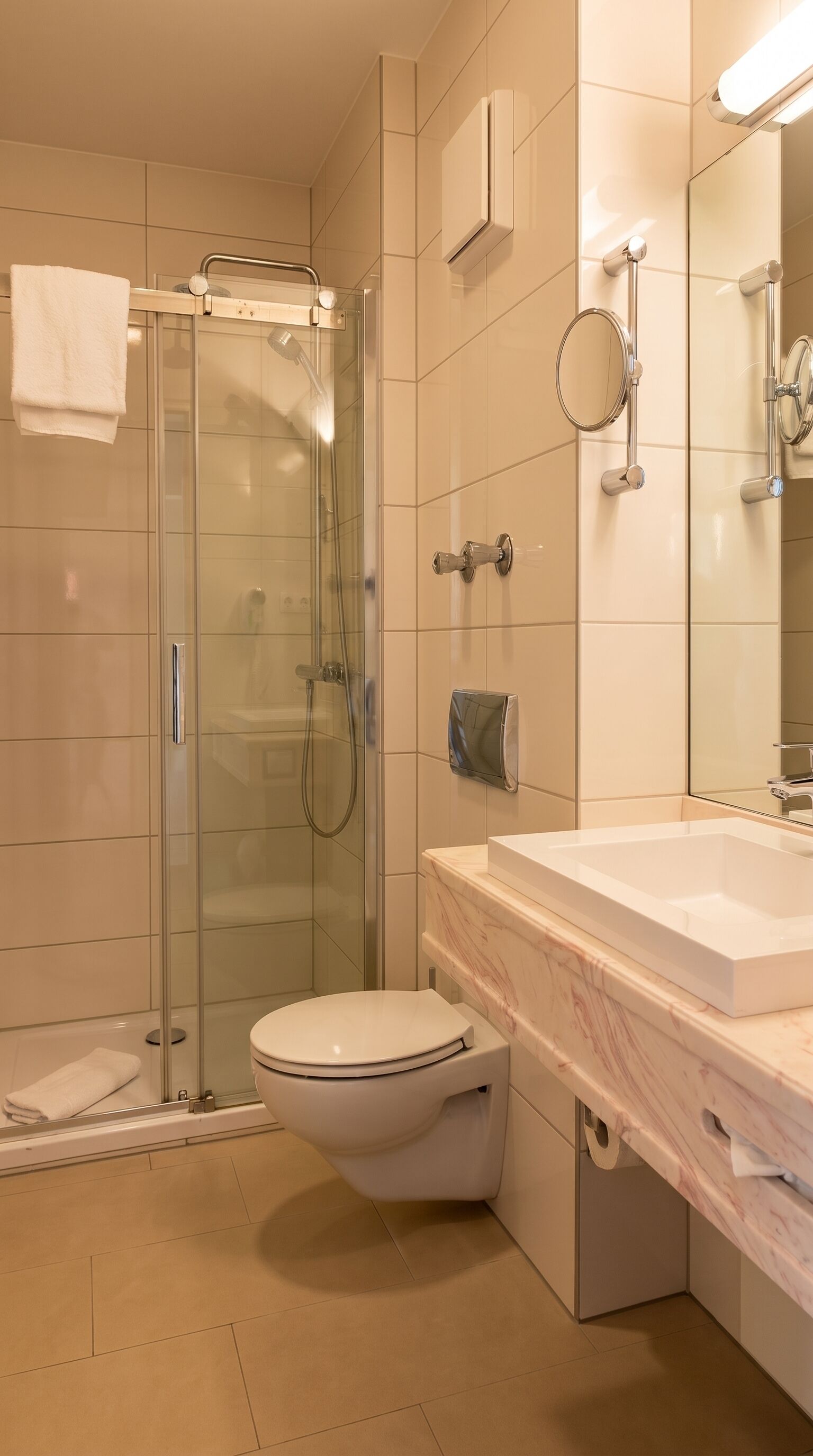 Ein modernes Badezimmer mit einer gläsernen Duschkabine, einer weißen Toilette und einem мраморном Waschtisch.