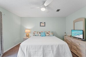 A bedroom with a bed, a nightstand, a dresser, a ceiling fan, a television, and a framed picture on the wall. - Sleeps 4 2 Bedroom Beach Access Across Street Pool (PANAMA CITY BEACH)