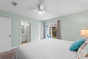 A bedroom with a bed, a ceiling fan, a door leading to a bathroom, and a view of the outside. - Sleeps 4 2 Bedroom Beach Access Across Street Pool (PANAMA CITY BEACH)