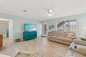A spacious living room with a teal cabinet, a beige sofa, and a television on a stand. - Sleeps 4 2 Bedroom Beach Access Across Street Pool (PANAMA CITY BEACH)