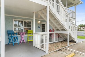 A building with a porch, a staircase, and colorful chairs. - Sleeps 4 2 Bedroom Beach Access Across Street Pool (PANAMA CITY BEACH)