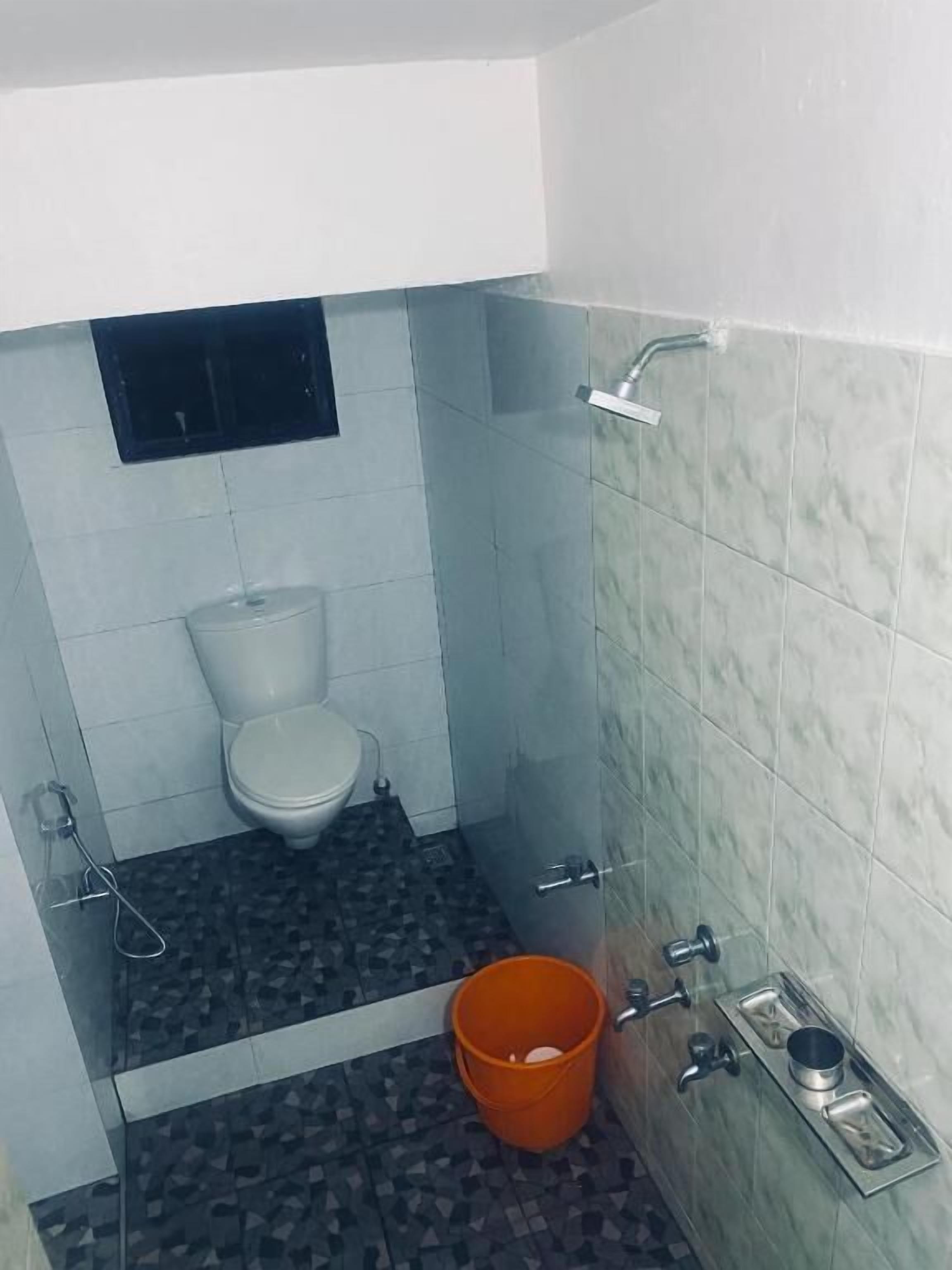 A bathroom with a toilet, a shower, and a sink.