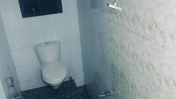 A bathroom with a toilet, a shower, and a sink.
