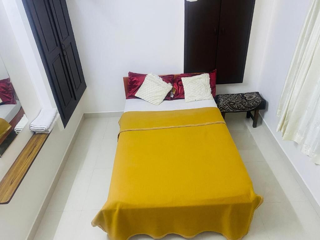A room with a bed, a small table, a wardrobe, and a curtain.