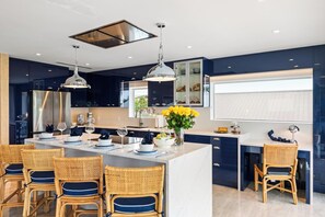 Una cocina moderna con armarios oscuros, una isla central con asientos e iluminación colgante.
