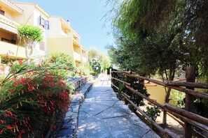 A narrow pathway flanked by buildings with balconies, leading to a gate. - Little House Nereids! Seafront vacation! (Quartu Sant'Elena)