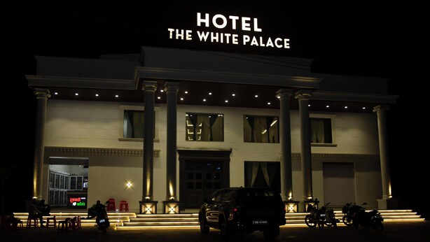 A hotel named 'The White Palace' with a grand entrance, large columns, and a well-lit facade. - Hotel The White Palace (Lakhpat)