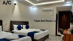 A triple bed room with three beds, a ceiling fan, an air conditioning unit, and a desk with a chair. - Hotel The White Palace (Lakhpat)
