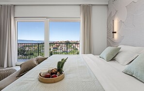 Ein Hotelzimmer mit einem großen Bett, Blick auf die Stadt und einem Balkon mit Geländer.