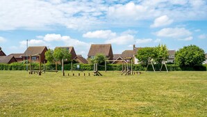 Un champ d’herbe avec des jeux pour enfants et des maisons en arrière-plan.