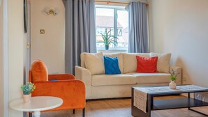Un salon avec un canapé, une table basse, un fauteuil et une fenêtre avec des rideaux.