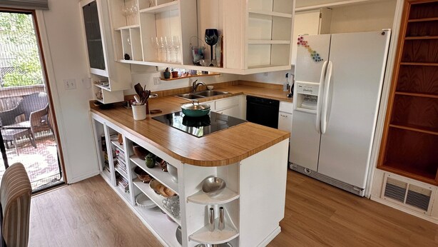 Eine moderne Küche mit weißen Schränken, einer Holz Arbeitsplatte und einem eingebauten Geschirrspüler.