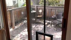 Eine Glasschiebetür führt zu einer Terrassenauslage mit Holzzaun, Tisch und Stühlen.