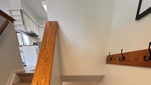 Eine Holztreppe mit Geländer, weißen Wänden und einem Holzregal mit Haken.