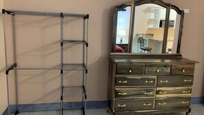 Een metalen schap en een houten dressoir met laden tegen een muur.