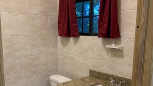 Een badkamer met toilet, wastafel en raam met gordijnen.
