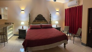 Een slaapkamer met een bed, twee bedlampen, een stoel, een bureau en een rood gordijn.
