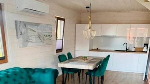 A modern kitchen with white cabinets, a dining table with chairs, and a hanging light fixture. - Two-story holiday homes with a pool, Mielno (Mielno)