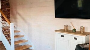 A room with a staircase, a flat-screen TV, a white cabinet, and a small table with decorative items. - Two-story holiday homes with a pool, Mielno (Mielno)