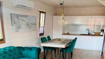 Un coin repas avec une table et des chaises, une cuisine en arrière-plan et un luminaire au plafond.