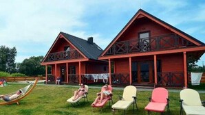A red wooden building with a balcony and a covered porch area. - Two-story holiday homes with a pool, Mielno (Mielno)